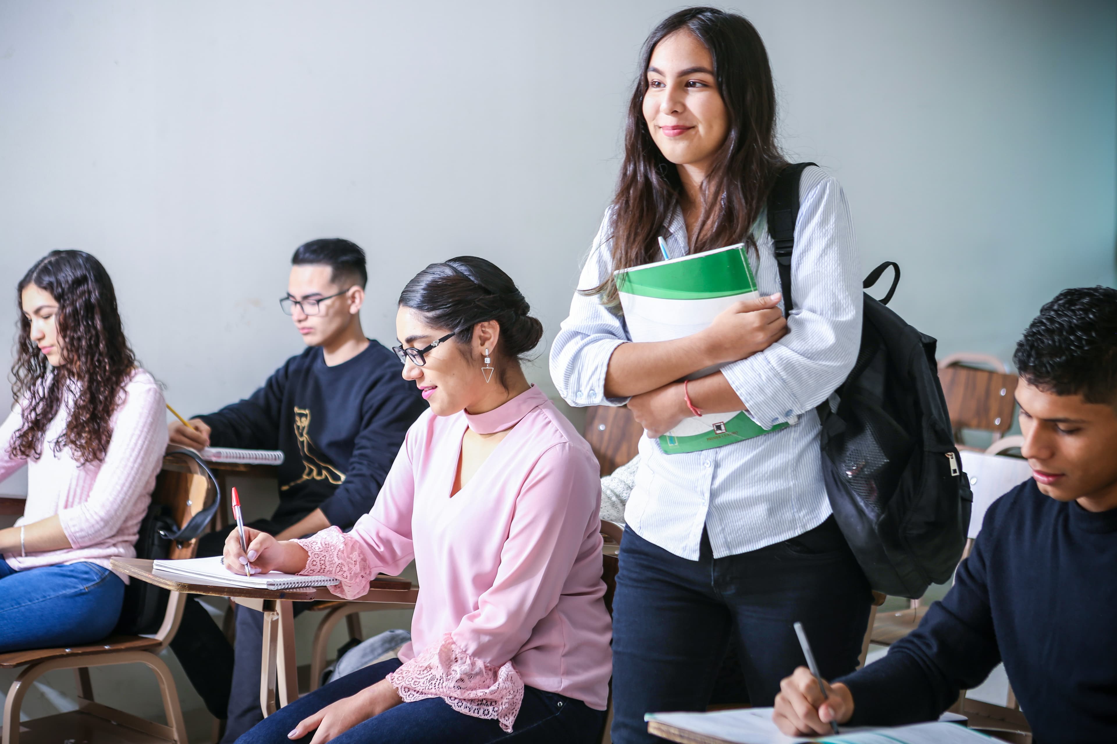 Student taking notes in a notebook during class